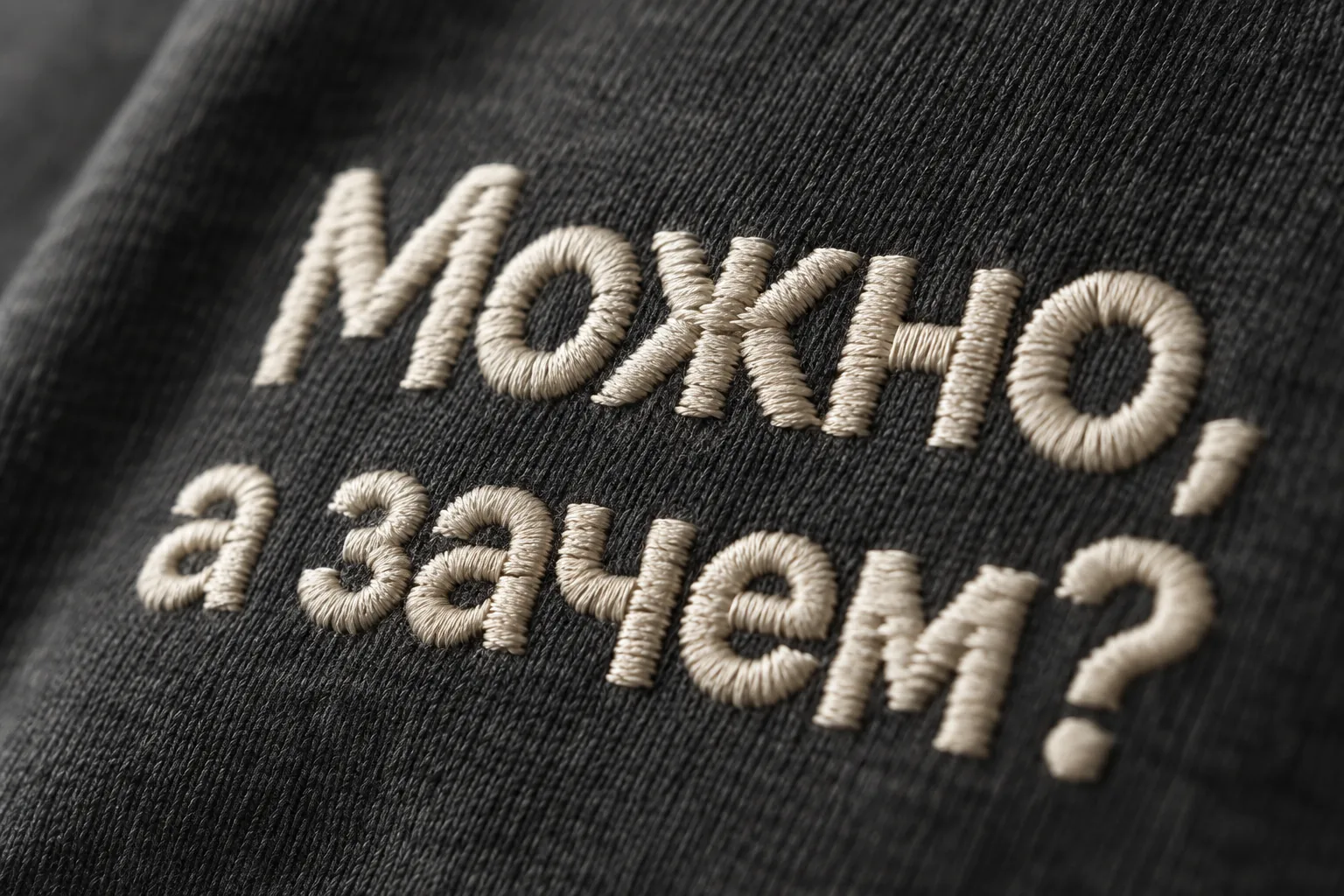 Женщина в чёрной оверсайз-футболке в профиль с небольшой светлой вышивкой «Можно, а зачем?» у сердца